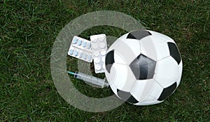 Football, a syringe in a soccer ball and pills on the lawn. The concept of doping in sports. Pharmaceuticals, championship.