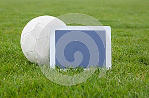 Football and tablet with blank screen on pitch