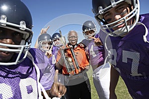 Football Team And Coach With Trophy Celebrating Victory On Field