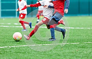 Football teams - boys in red, blue, white uniform play soccer on the green field. boys dribbling. dribbling skills.