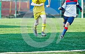 Football teams boys in yellow white sportswear play soccer on the green field. Dribbling skills. Team game, Training,