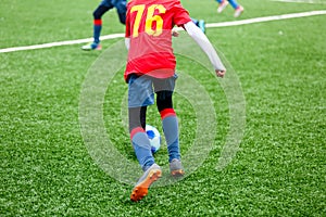 Football training for kids. Boys in blue red sportswear on soccer field. Young footballers dribble and kick ball in game.