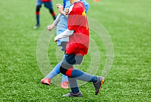 Football training for kids. Boys in blue red sportswear on soccer field. Young footballers dribble and kick ball in game. Training