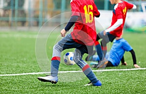 Football training for kids. Boys in blue red sportswear on soccer field. Young footballers dribble and kick ball in game. Training