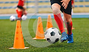 Footballer dribbling ball on training between orange cones