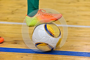 Footballer foot knocks the ball after an strike from the sideline in a mini-football in the hall