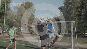 Footballer heading ball to score goal on pitch