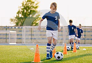 Footballer running with ball on training pitch. Soccer practice for junior level team