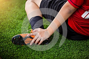 Footballer is sitting and catch the ankle of the feet because of pain, soccer player was injured in the foot