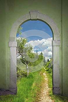 Footpath through arched door into wild bogland