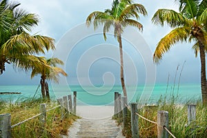 Footpath on the beach to the beautiful green ocean.