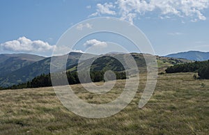 Chodník turistického chodníka z hrebeňa chopku s horskou lúkou, kosodrevinou a výhľadom na modrozelený hrebeň