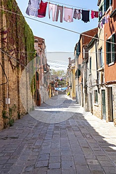 Footpath of a narrow residential alley with clothes hanging for drying on clothesline