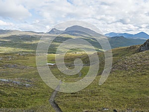 Footpath in northern artic landscape, tundra in Swedish Lapland with green hills and mountains at Padjelantaleden hiking