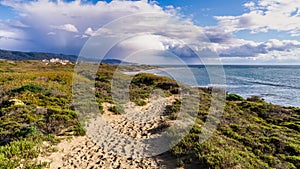 Footpath on the sand dunes of Ano Nuevo State Park; storm clouds visible in the background; Pacific Ocean Coastline, California