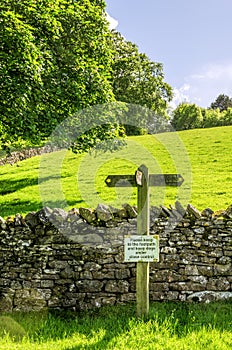 Footpath sign on a sloping green field