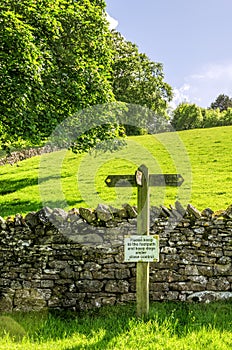 Footpath sign on a sloping green field photo