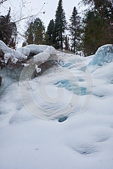 Footpath in winter taiga forest under heavy snow along Tevenek river on the bank of Teletskoe lake. Altai