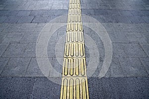 Footpath with yellow tactile paving for blind people walking safely on the sidewalk photo