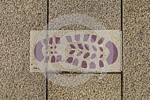 Footprint of a boot painted on the ground that guides the pilgrims along the Camino de Santiago. Galicia, Spain.