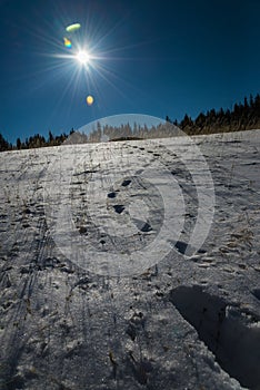 Footprint on snow and blue sky with Sun flare