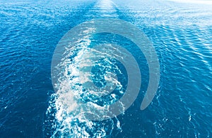 Footprint on the water from the ship. White wave on blue water. Blue sea water. Water and sky