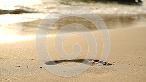 Footprints on beach sand and surging wave