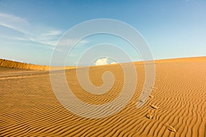 Footprints on beautiful sand dunes with blue sky and white clouds