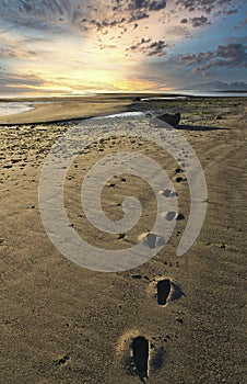 Footprints on an empty beach at sunset