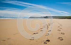 Footprints of hiking boots on the sand of a remote beach