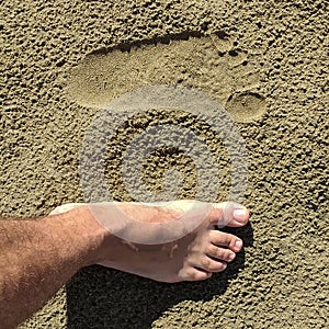 Footprints of human feet on the warm sand photo