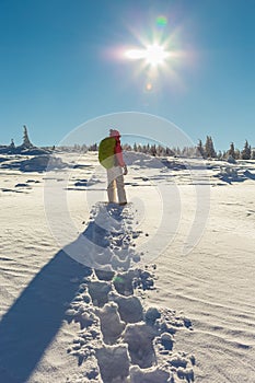 Footprints leading to young woman snowshoeing on a sunny day