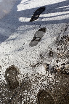 Footprints in melting snow. Snow texture with shoeprints.