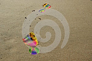 Footprints in rainbow colors on the beach