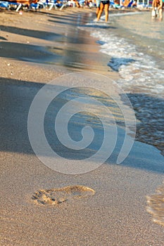 footprints on sand beach along the edge of sea.