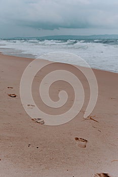 footprints in the sand. beach, wave and footprints on a sandy beach. Sea, sand. cloudy sky.