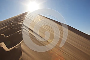 Footprints on sand dune into the sun