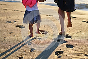 Footprints in sand. Feet of mother and child walk along shore. Summer memories.