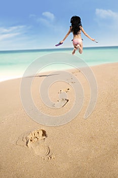 Footprints on sand and jumping woman