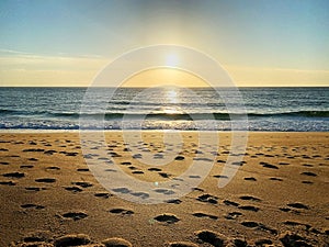 Footprints in the sand at sunset, beach, wave and footprints at sunset time