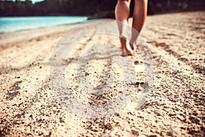 Footprints on the sand with walking girl on background