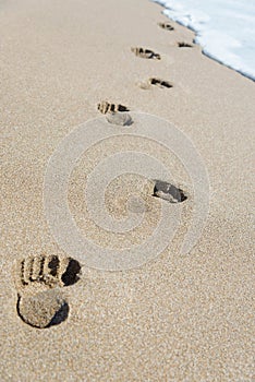 Footprints on sea beach sand with wave foam