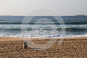 Footprints on the Shoreline with a Garbage Bin