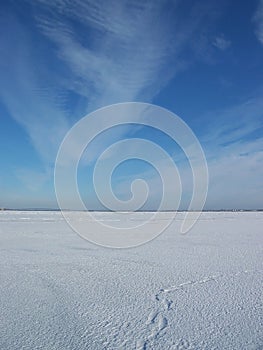 Footprints in the snow going away. walk in Baikal. bright blue sky with feathery clouds on a Sunny winter day