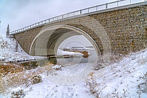 Footprints on snowy trail passing under a bridge