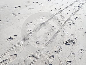 Footprints and tire tracks in sand on beach