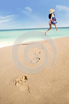 Footprints and woman running at beach