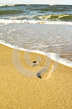 Footprints on the yellow sand flooded with sea waves