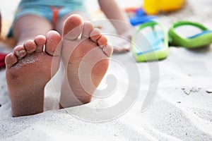 Foots of little girl at the beach and slates nearb