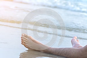 Foots of man relaxing on beach